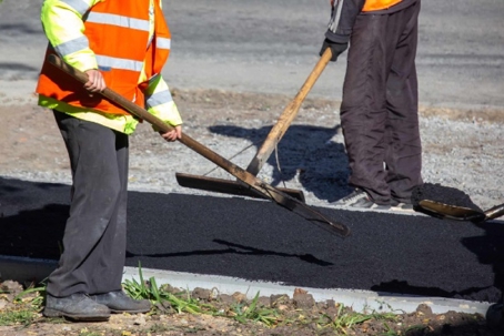 two people smoothing fresh asphalt